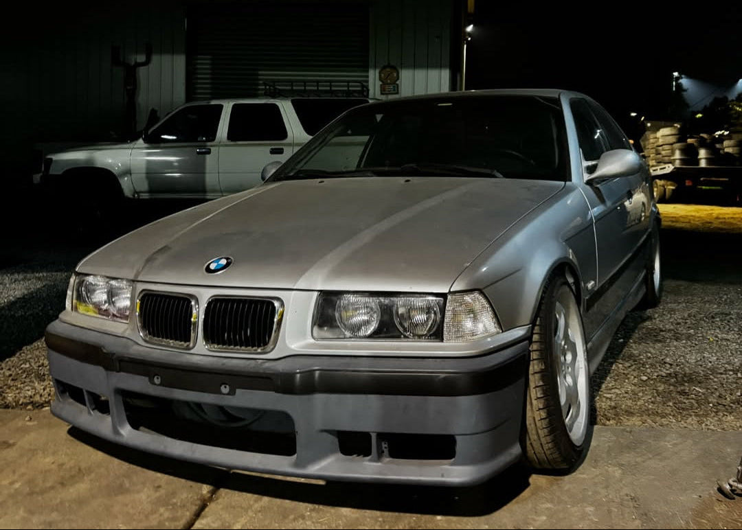 Gray BMW car parked in front of a red building at night